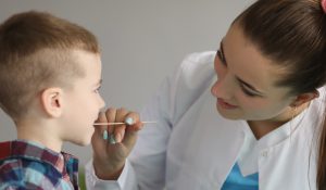 a nurse swabbing a young boy's mouth for a saliva sample
