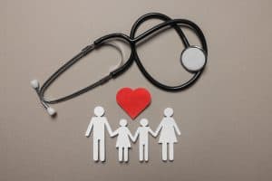Picture of a stethoscope and paper cutouts of a heart and a family.