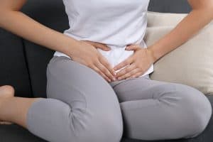 Woman experiencing a painful urinary tract infection while sitting on sofa at home