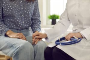 Picture of a doctor holding a patient's hand and comforting her as they discuss a medication-assisted opioid treatment program.