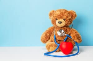 Picture of a teddy bear, a stethoscope, and a small red heart figurine.