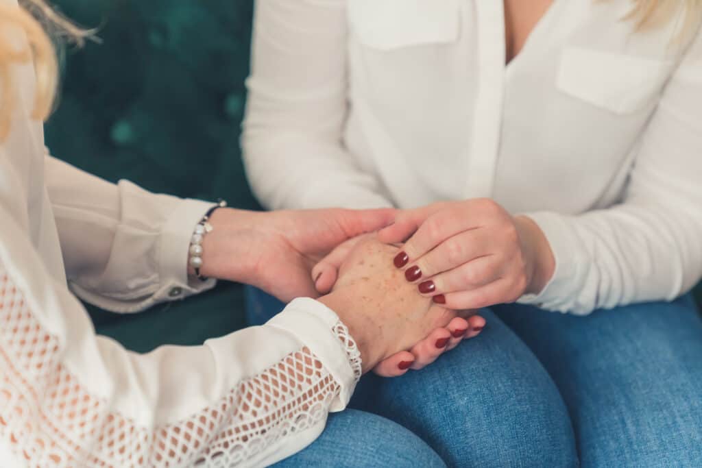 Picture of a woman holding the hands of a loved one who is going through medication-assisted treatment.