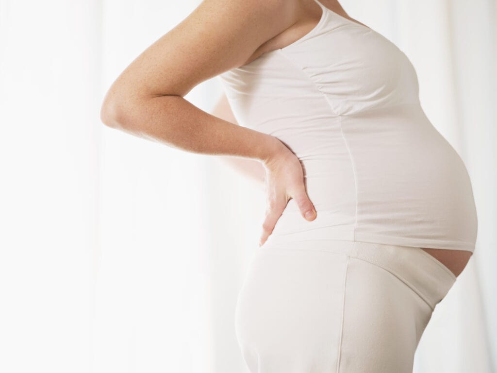 Picture of a pregnant women standing with her hands on her hips.