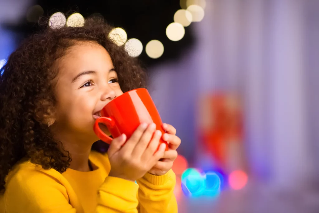 young girl drinking out of a red mug